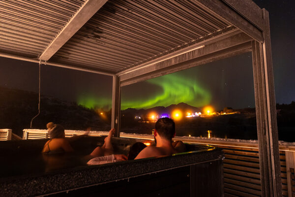 Vikran seaside lodge-mennesker sittende på verandaen og ser på nordlys